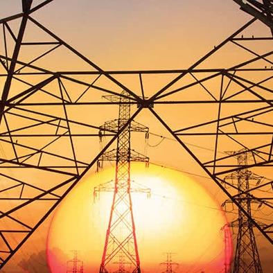 An image of electrical utility towers in front of a sunset.