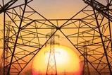 An image of electrical utility towers in front of a sunset.